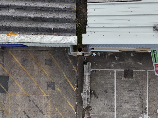 Aerial view showing a split between two different surfaces and a drainage pipe.